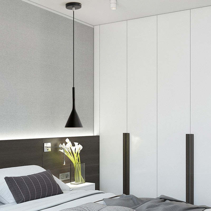 Black cone pendant and round canopy beside a bed with white wardrobe doors, dark headboard and white flowers