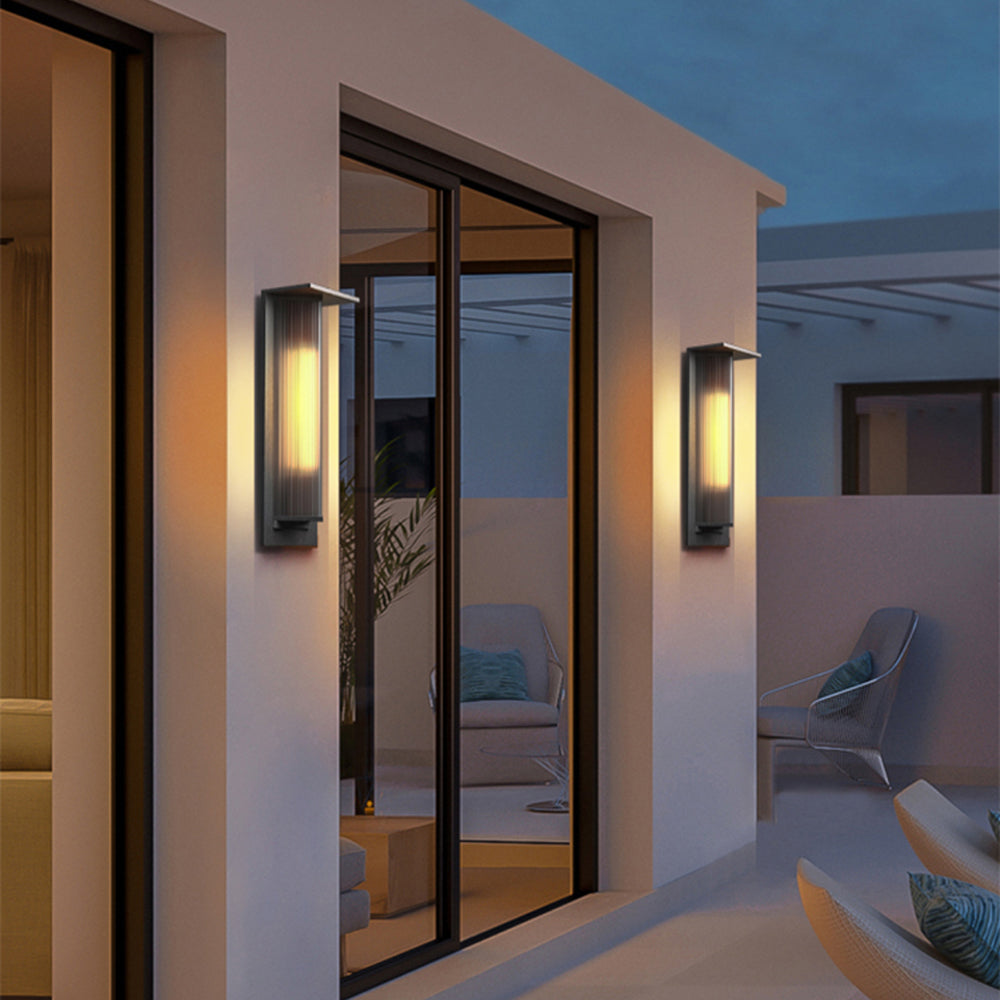 Two glowing Orr ribbed wall lights by a large exterior window
