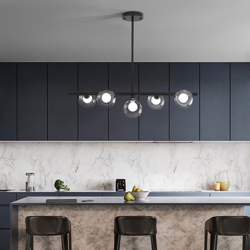 Black five-globe pendant with a lower central globe above a kitchen island and dark cupboards