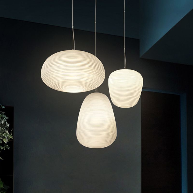 Wide, tall and compact white ribbed pendants suspended separately in a dark interior