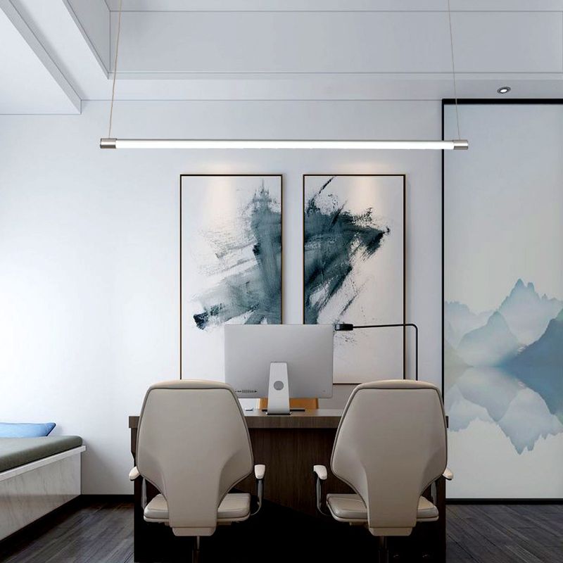 Silver-endcap linear pendant above an office desk with a monitor, two chairs and abstract artwork