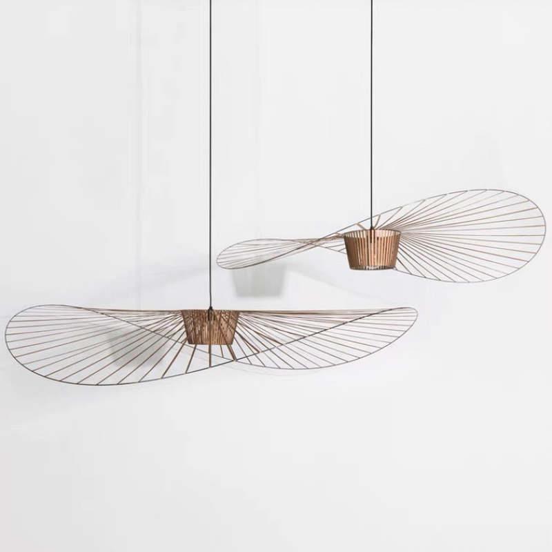 Two separate golden-brown wavy radial-line pendants suspended at different heights against a white wall