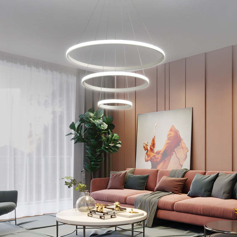 White three-ring pendant light arranged in horizontal descending levels above a Coral sofa, coffee table, plant and artwork