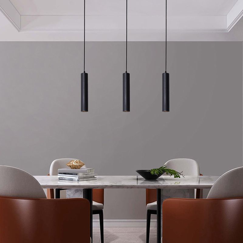 Three slim black Edge pendants above a dining table.