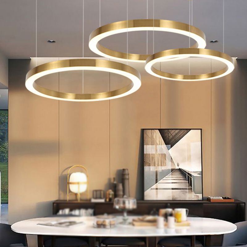Three separate gold-colour ring pendants styled above a dining table