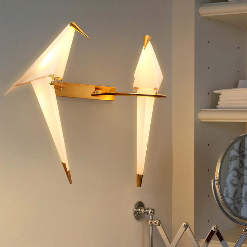 Two illuminated Clifford birds on one rectangular gold-tone plate beside shelves and a round extending mirror