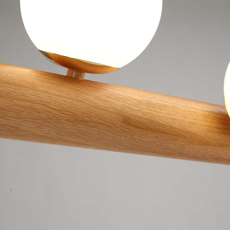 Close-up of wood grain on a cylindrical bar and a Gold-tone collar beneath a White glass globe