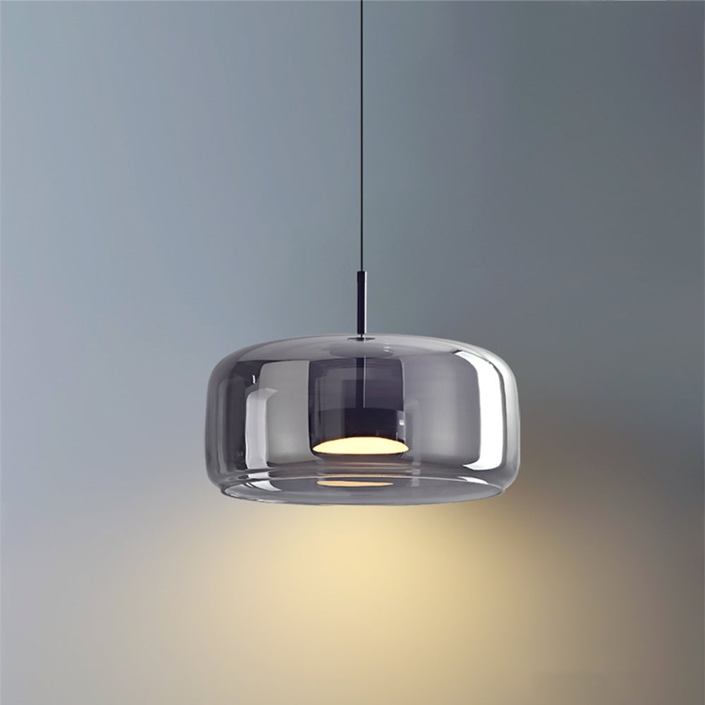 Close view of broad smoky-gray Hailie glass shade, dark stem and glowing circular light housing against gray wall