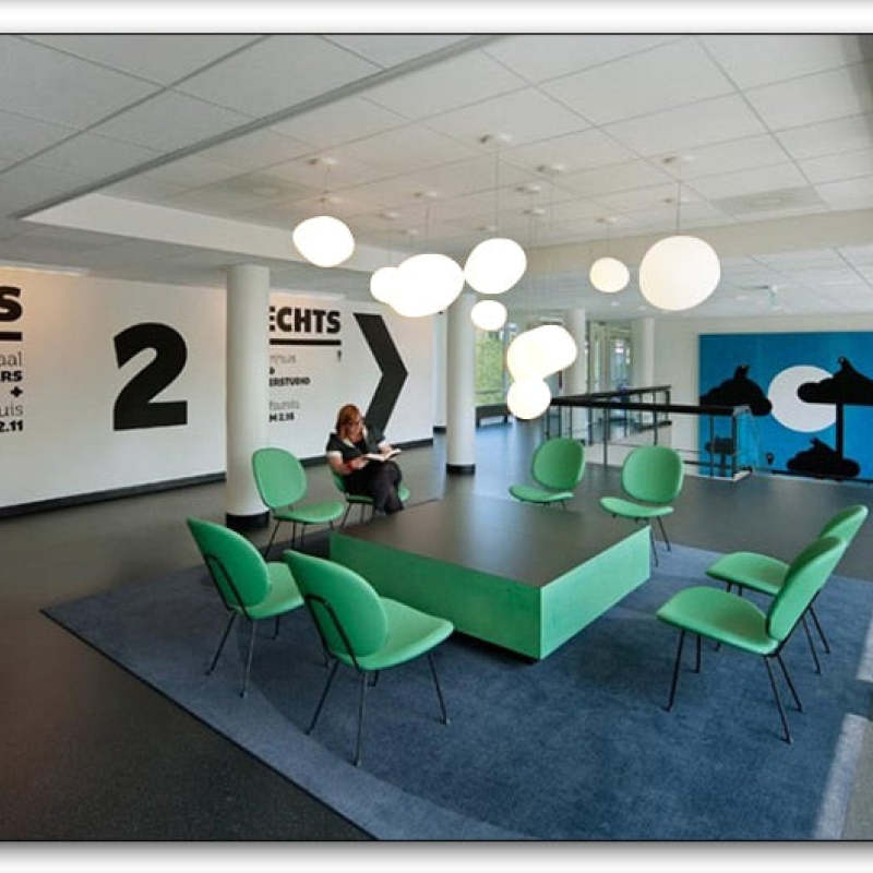 Multiple white pendants above green meeting tables