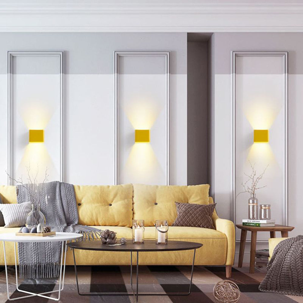 Three yellow wall lamps above a sofa in a living room