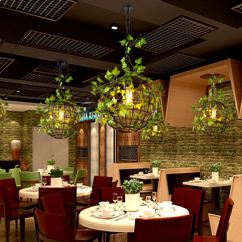 Green vine-decorated Nest pendants above round restaurant tables.
