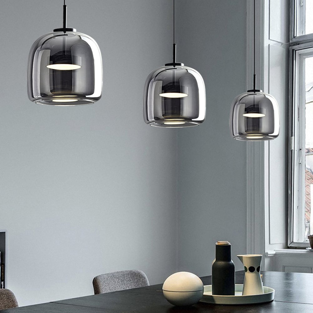 Three tall smoky-gray Hailie glass pendants above dining table with vases, gray chairs and window