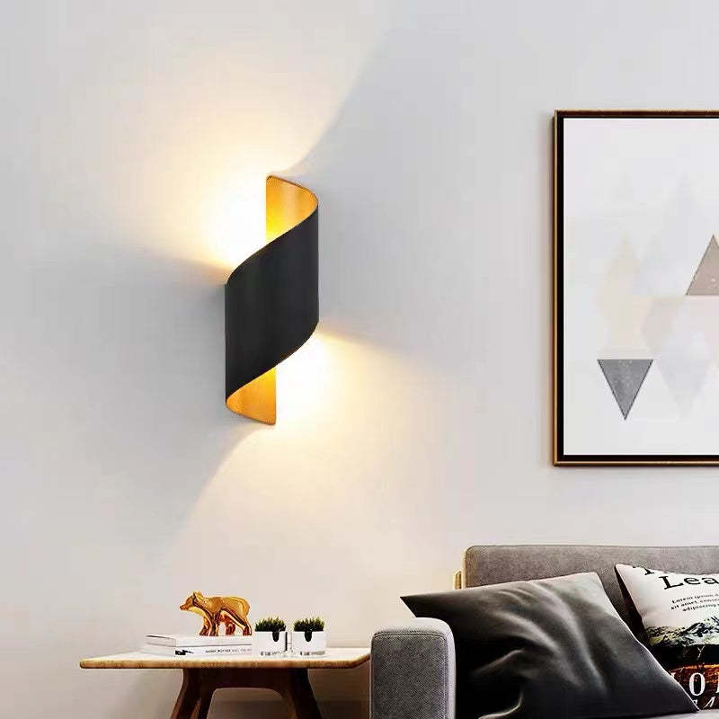 Black and gold curved wall light beside framed artwork above a grey sofa and wooden table