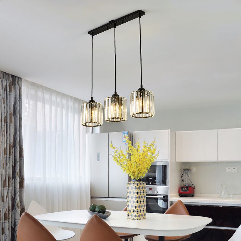 Black three-cylinder glass row over pale breakfast counter with yellow flowers, refrigerator and built-in oven