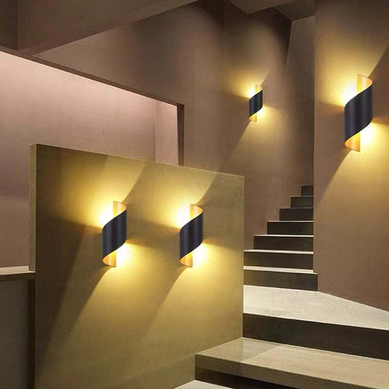 Four curved black and gold wall lights arranged around stair flights and a partition
