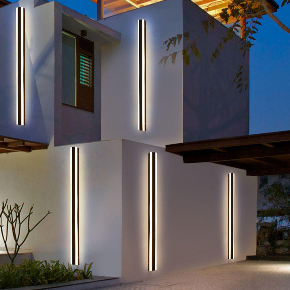 Five long Black Orr wall-light bars with white illuminated edges on an exterior facade at dusk