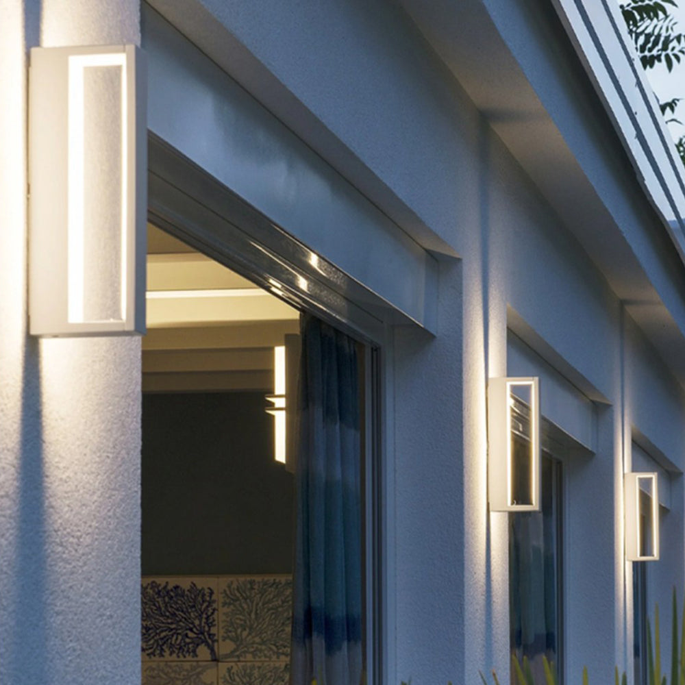 White open-frame wall lights glowing beside glazed doors beneath exterior eaves