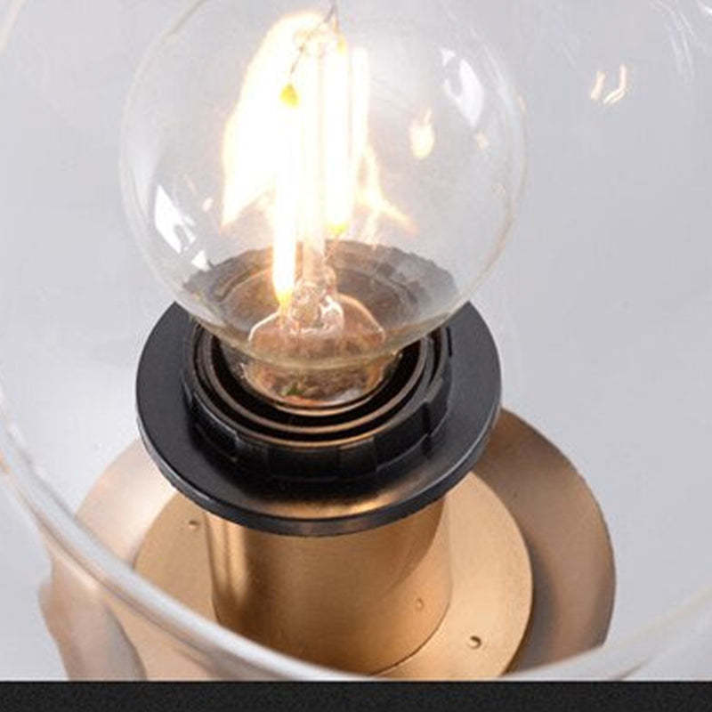 Close lit filament-looking bulb, dark socket ring and gold-tone holder inside a clear Valentina globe