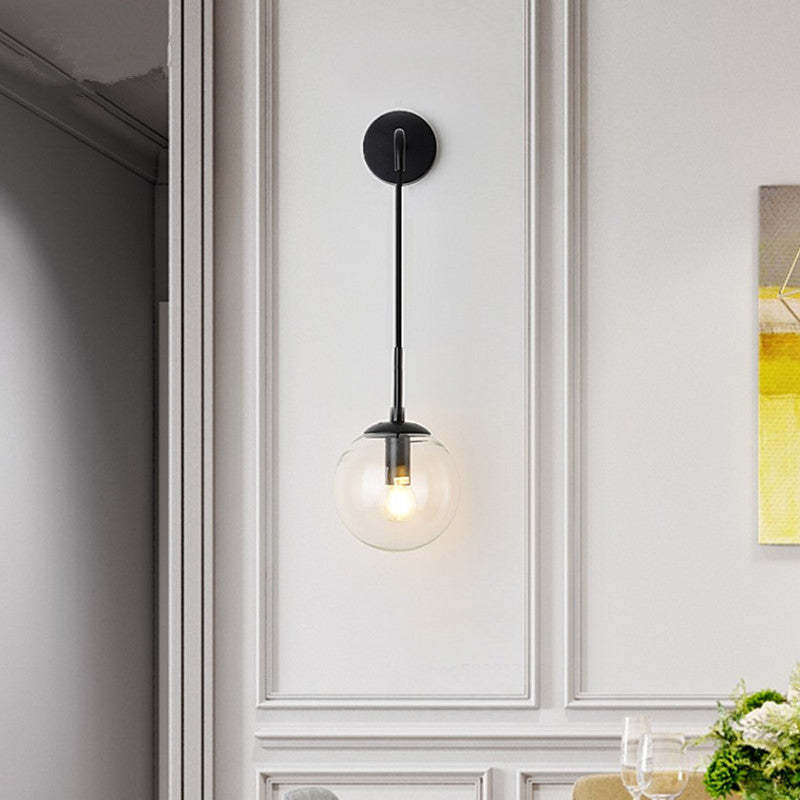 Black glass globe wall light with a clear shade against decorative wall moulding