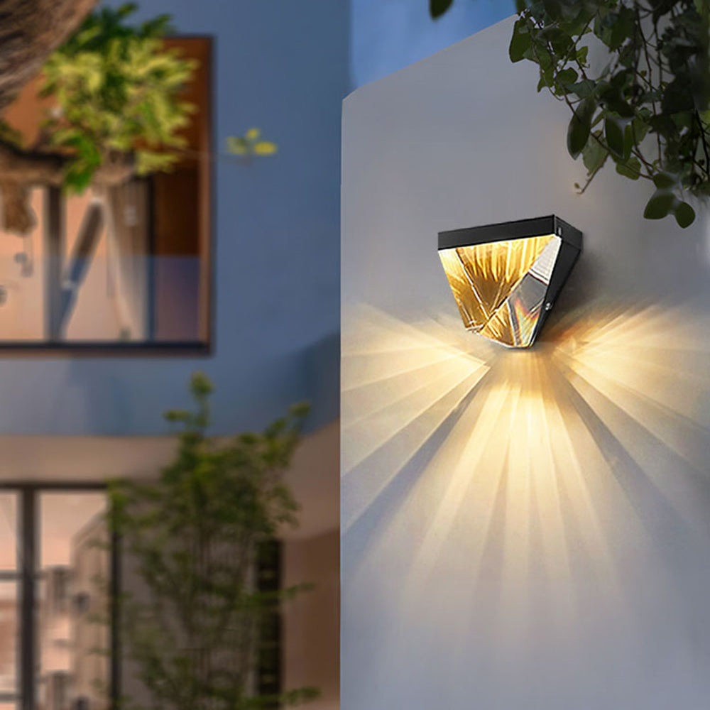 Close view of black Orr faceted wall light casting warm rays down an exterior wall