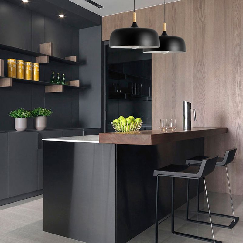 Two black deep dome pendants above a kitchen island with bar stools and wood paneling