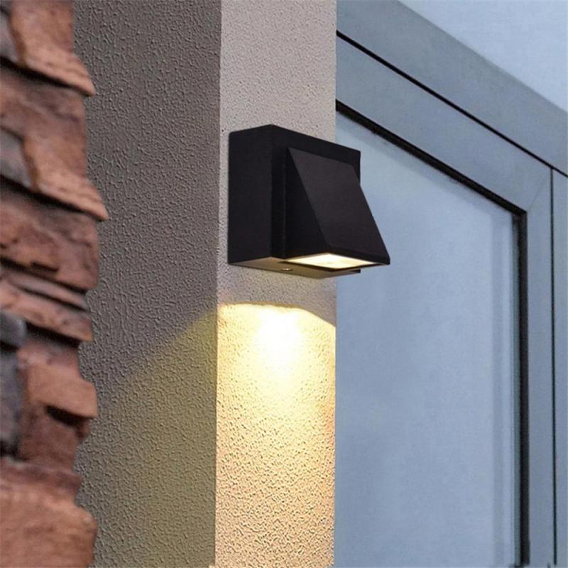 Black Orr single-head wall light casting a downward beam by a doorway