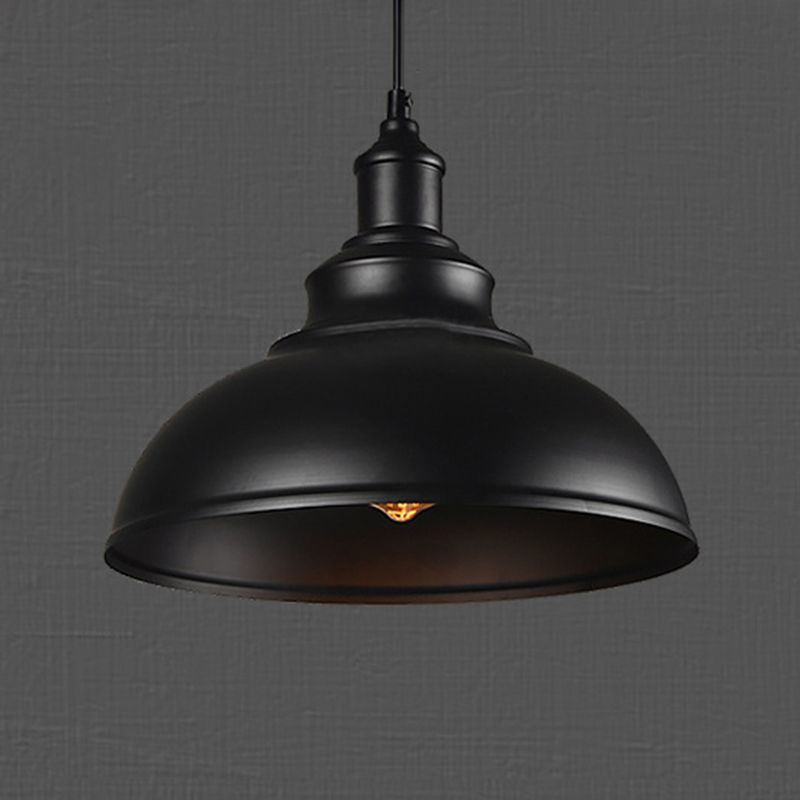 Angled underside of a black dome pendant with a black upper fitting and a glowing bulb beneath the shade
