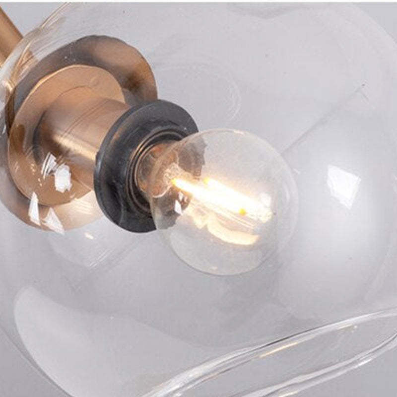 Close glowing filament-looking bulb, dark holder and gold-tone cup inside an open clear globe
