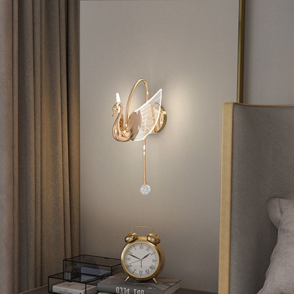 Kady Rose Gold swan wall light beside a bed with clock, books and curtain