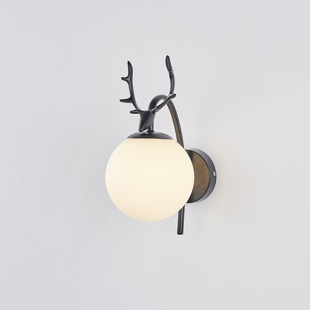 Lit angled Black Valentina with warm-looking white globe and antlered deer head on a pale gray wall