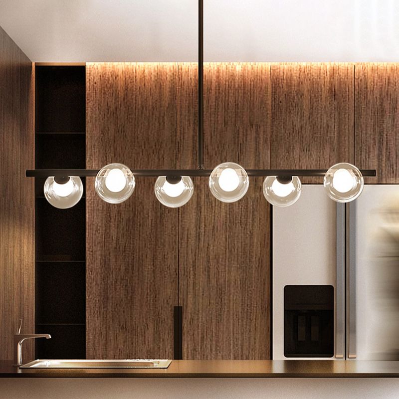 Valentina six-light black pendant above an island near wood panels, refrigerator and sink