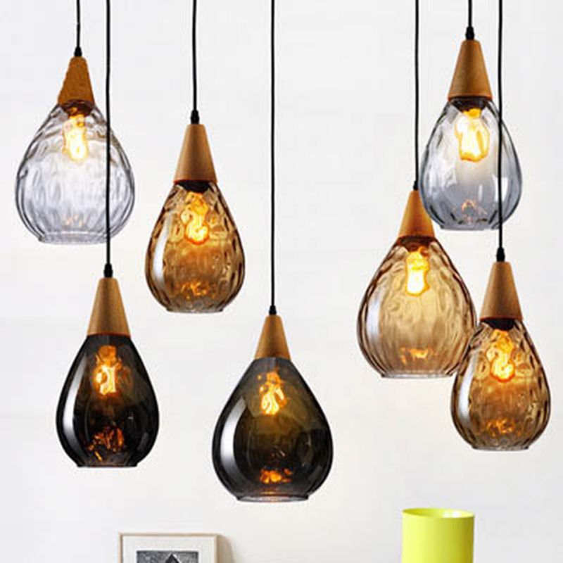 Multiple clear, amber and smoke-gray Avi pendants in broad and narrow shapes at varied heights above pale interior