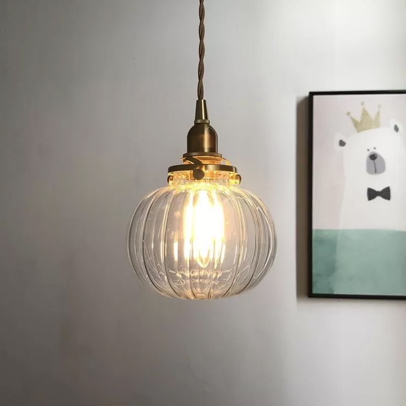 Clear ribbed glass globe pendant beside wall art