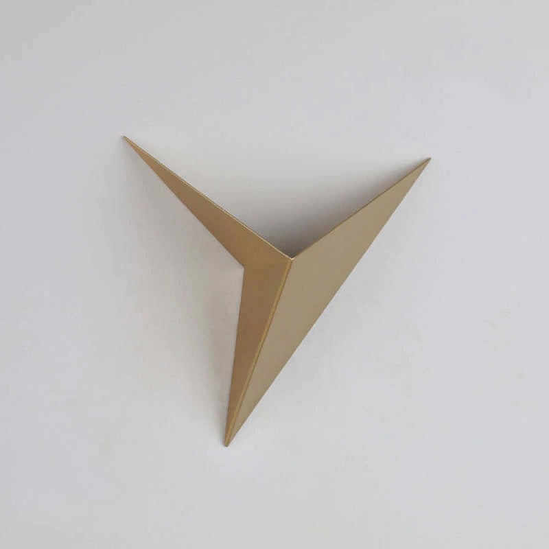 Gold Orr triangular wall lamp on a plain wall