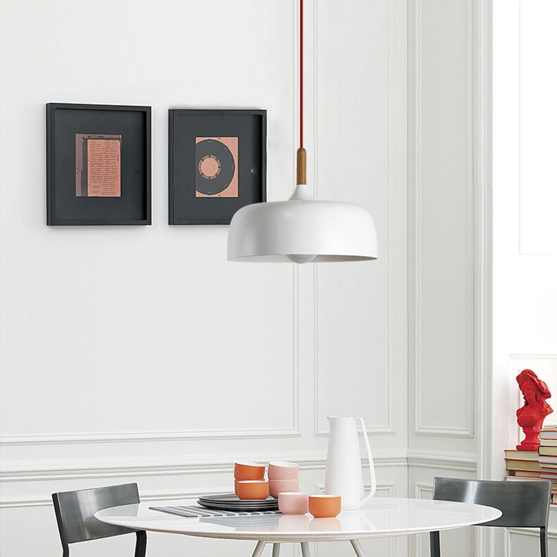 White deep dome pendant with a red cord above an oval dining table with colorful cups