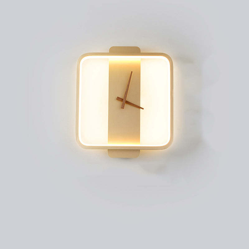 Front view of a Gold rounded-square wall light with warm-looking illuminated outline and Brown clock hands