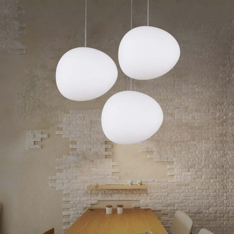 Three separate white glass pendants above a wooden table