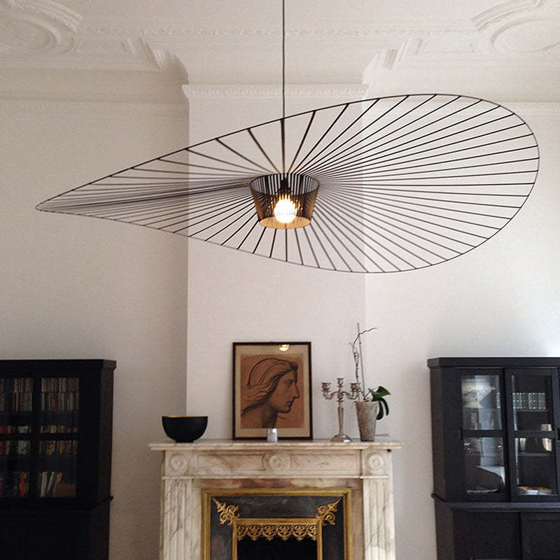 Wide black radial-line pendant with a wavy edge above a fireplace between dark display cabinets