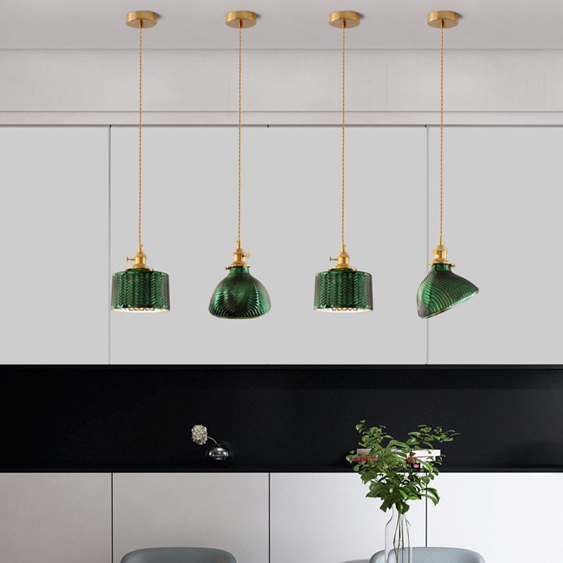 Four separately canopied green cylinder and flared pendants along a white interior counter