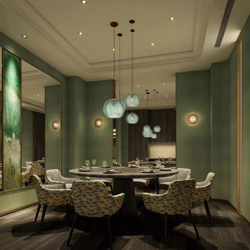 Green ribbed pendants arranged above a round dining table in a green room.