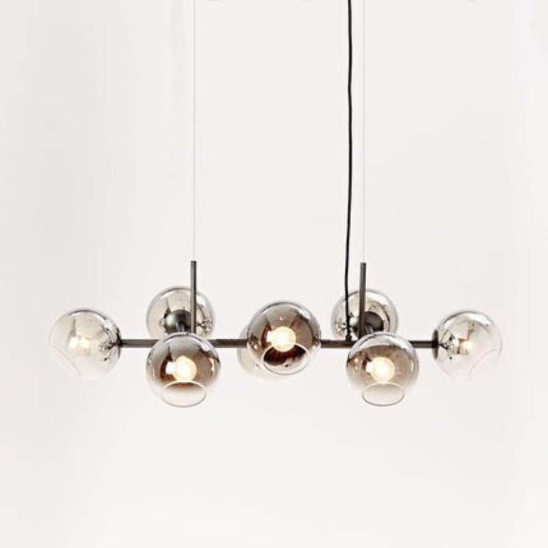 Black linear pendant with lit darker reflective open glass globes and long suspension cables on pale background
