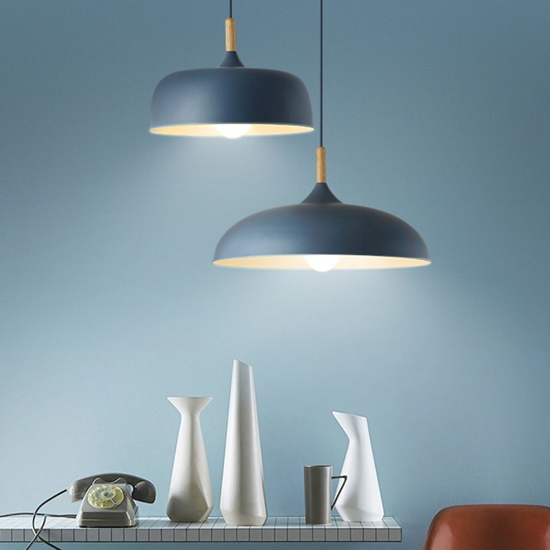 Two blue dome pendants with different shade profiles above a tiled console with white vases and a telephone