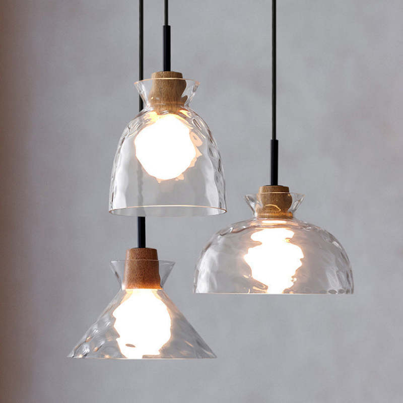 Three glowing clear glass pendants against grey wall