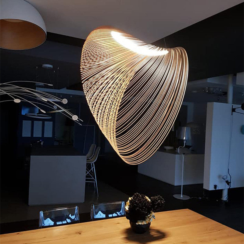 Ozawa pendant with curved wood slats and a lit upper rim above a wooden table in a dark interior