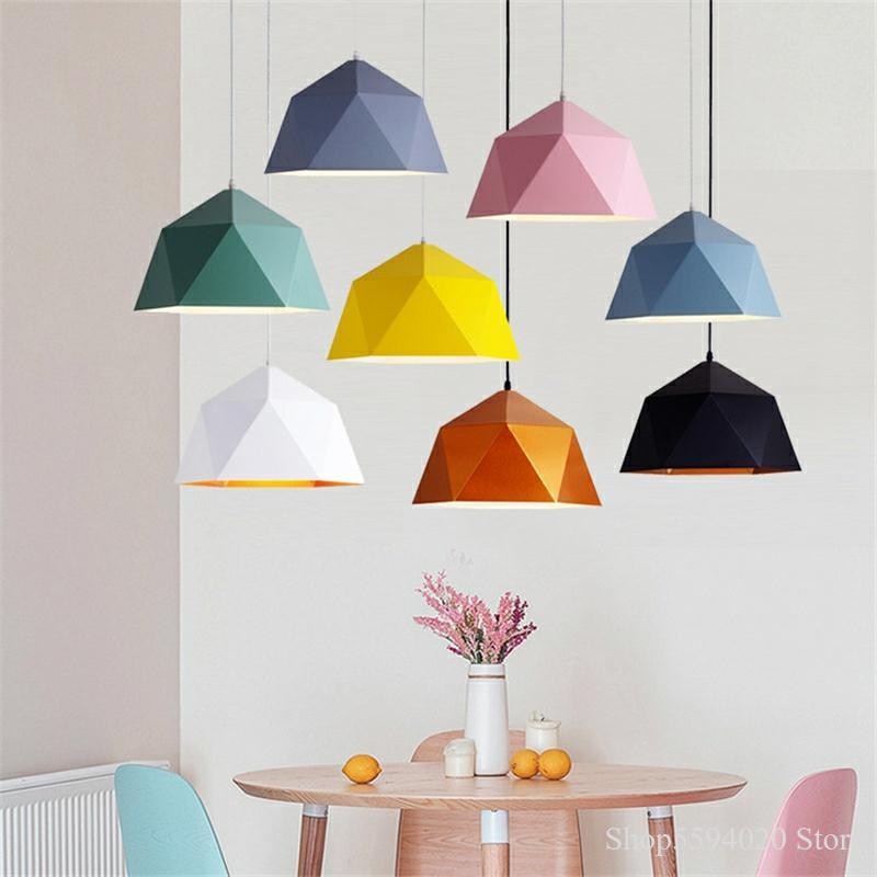 Mixed-color geometric pendant lights above a round dining table with pastel chairs and flowers