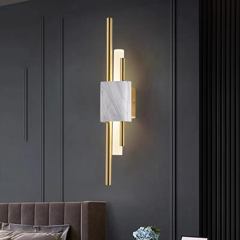 White-veined Alana wall light with gold-tone rods on a dark wall above an upholstered seat