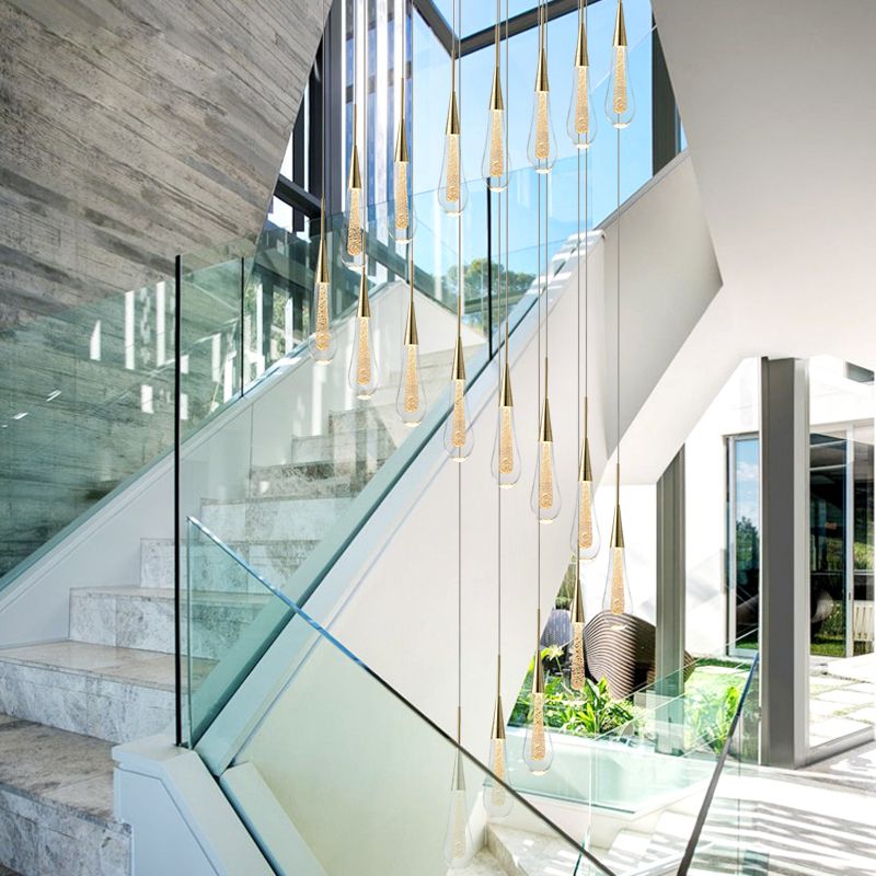 Multiple Hailie teardrop pendants cascading through a stairwell with glass balustrades and tall windows