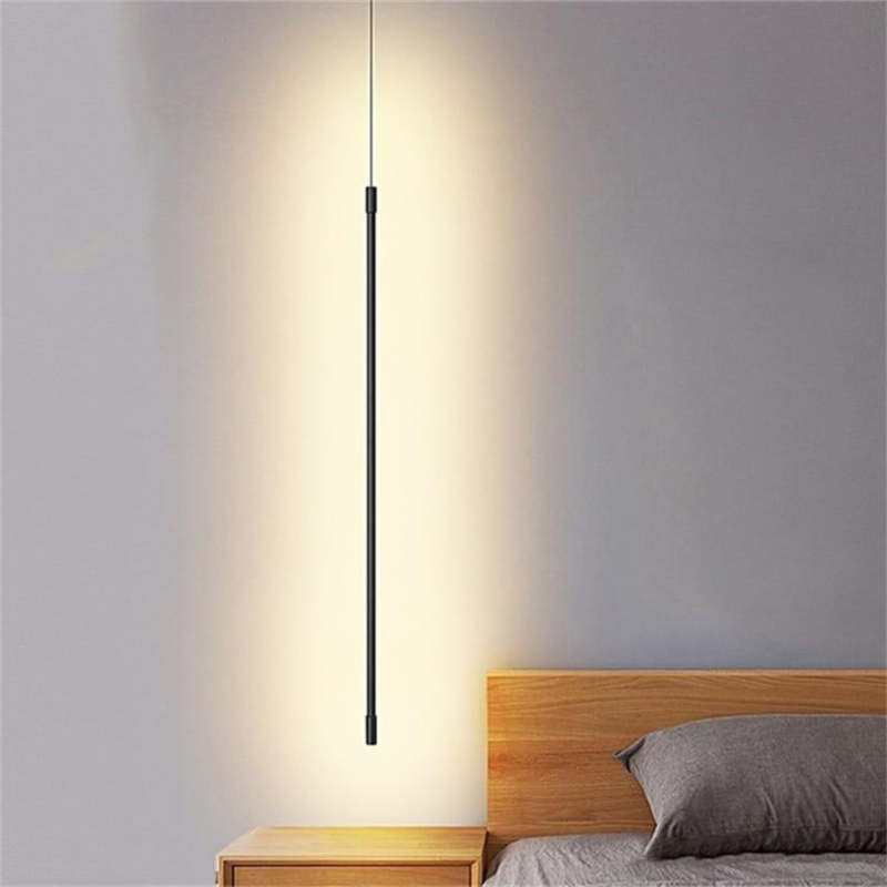 Illuminated Edge black rod pendant beside a wooden headboard and bedside table