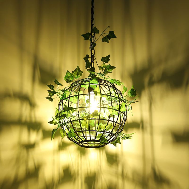 Illuminated Nest cage pendant casting leaf and frame shadows on a wall.