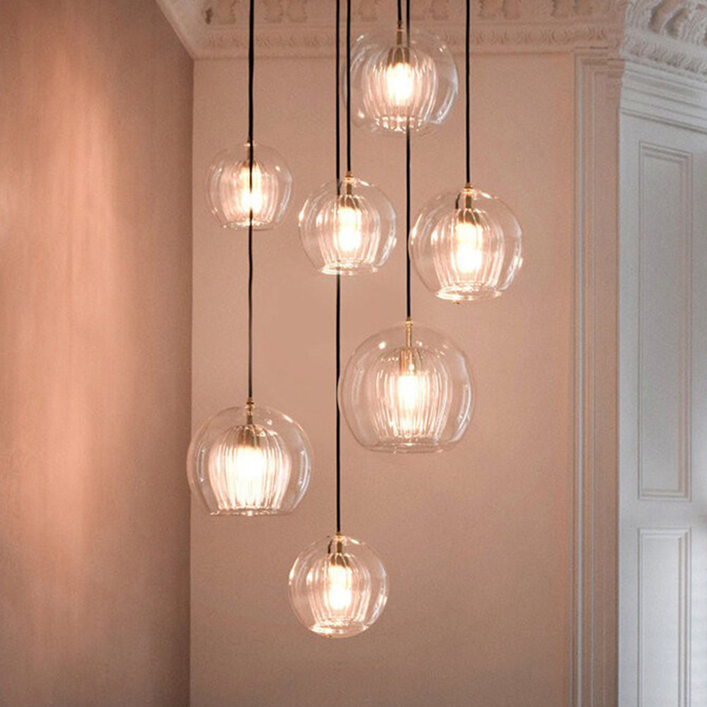 Clear globe pendants hanging at staggered heights beside a pale wall and doorway